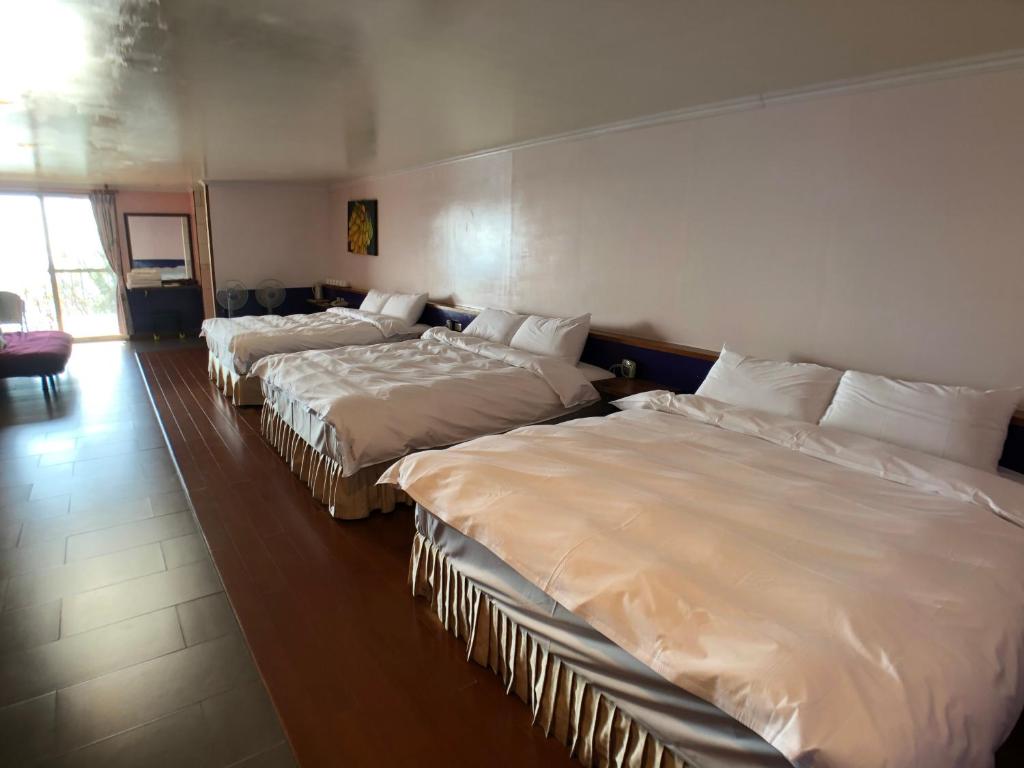 three beds in a hotel room with white sheets at Cingjing Four Seasons B&amp;B in Ren&#39;ai