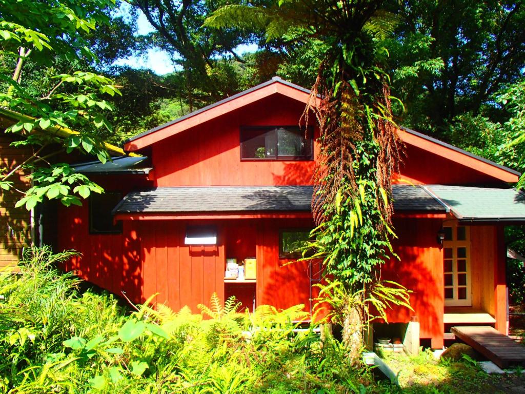 uma casa vermelha com uma árvore em frente em 屋久島コテージ対流山荘 em Yakushima