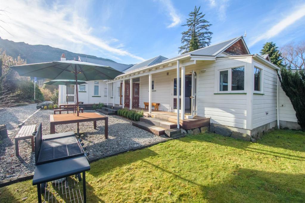 a white house with a picnic table and an umbrella at Willowbrook Country Apartments in Arrowtown