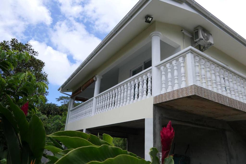 Cette maison blanche dispose d'un balcon. dans l'établissement Tropical Garden Self Catering, à Victoria