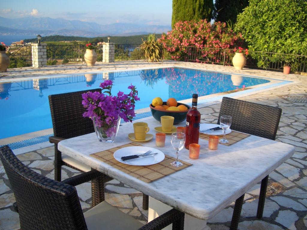 a table with wine glasses and a bowl of fruit next to a pool at Villa Bacchus Kassiopi Corfu in Kassiopi