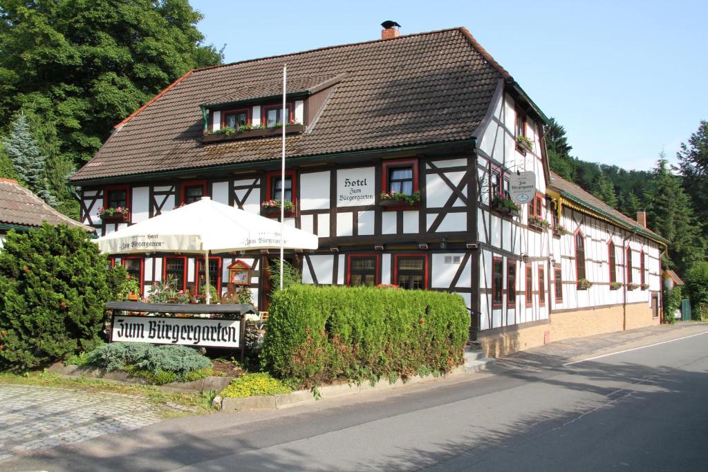 a black and white building with an umbrella at Hotel Zum Bürgergarten in Stolberg i. Harz