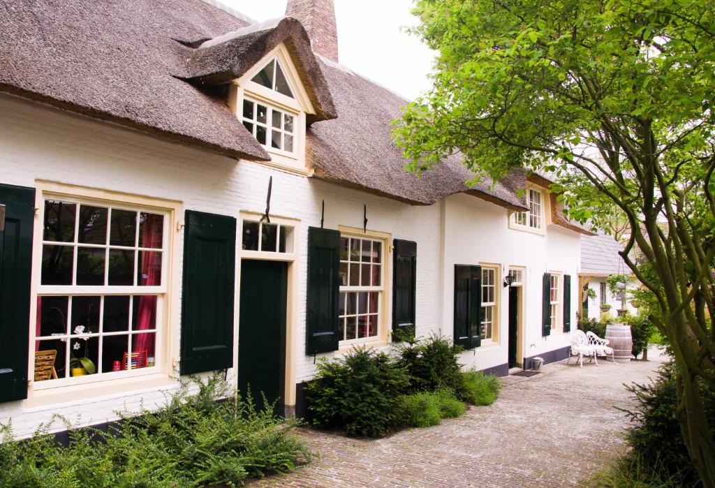 a white house with a thatched roof at Genesis Voorschoten in Voorschoten