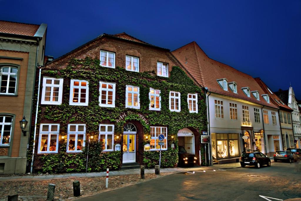 a building with ivy growing on it in a street at Hotel Bremer Hof in Lüneburg