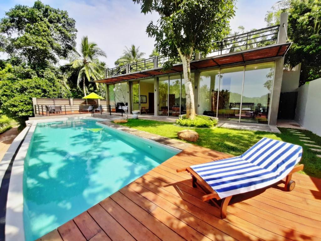 a house with a swimming pool and a deck at Sugoi House in Unawatuna