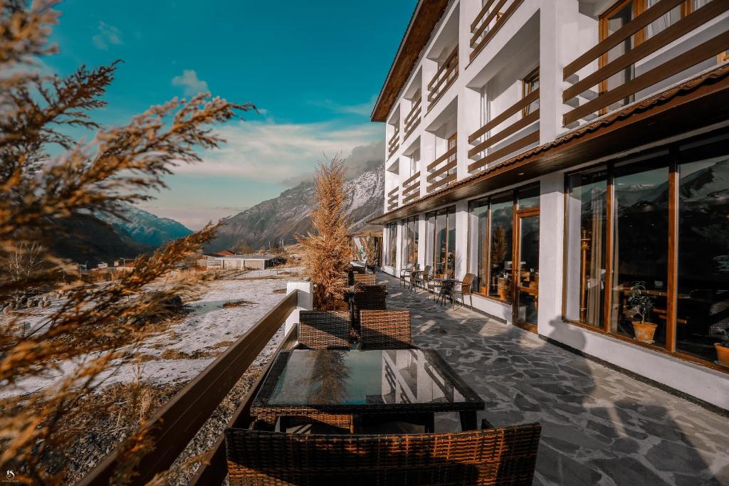 a table and chairs on a balcony with a view at Alpine Lounge Kazbegi in Stepantsminda
