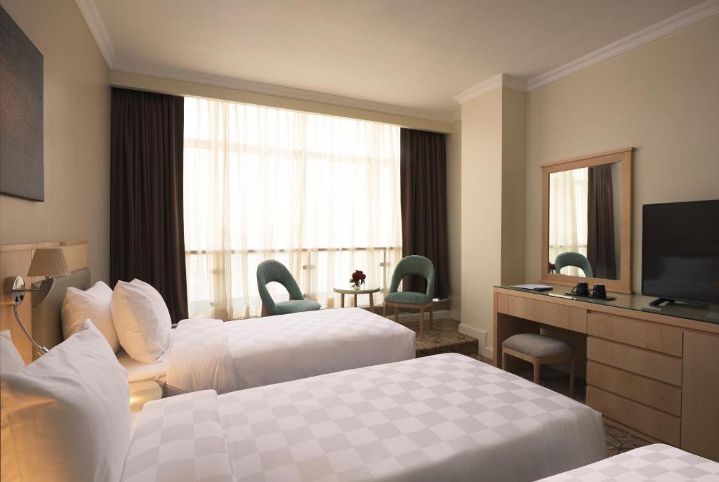 a hotel room with two beds and a television at Saja Al Madinah in Al Madinah
