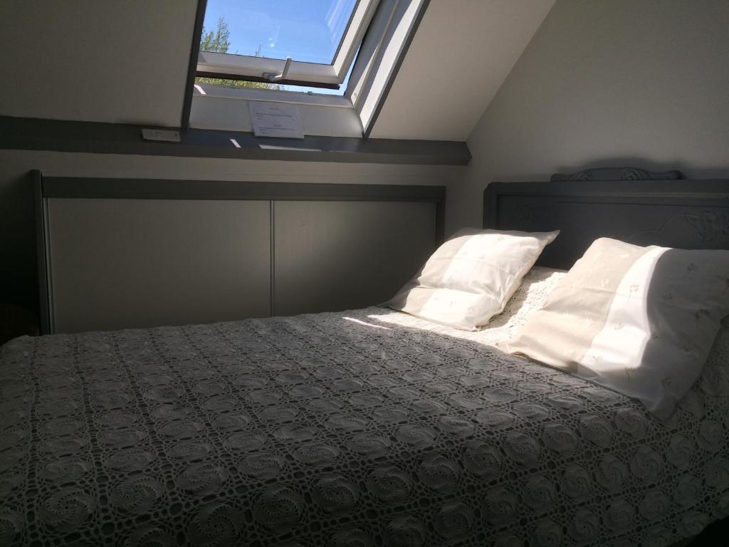 um quarto com uma cama com almofadas e uma janela em La Mansarde em Neuville-sous-Montreuil