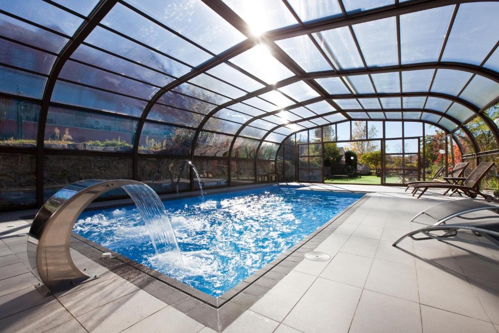 una piscina cubierta con techo de cristal y tobogán de agua en Luces del Poniente en Cercedilla