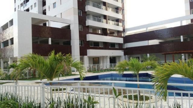 un edificio con una piscina y palmeras delante de él en Riviera CONDOMINIO Clube - BOA VIAGEM torre natura ap 1103, en Recife