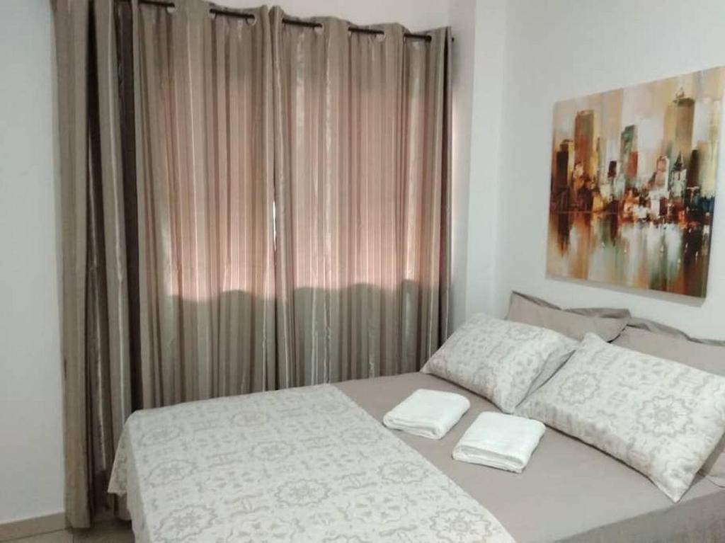 a bedroom with a white bed and a window at APARTAMENTO CIDADE VERDE 3 MT in Maringá