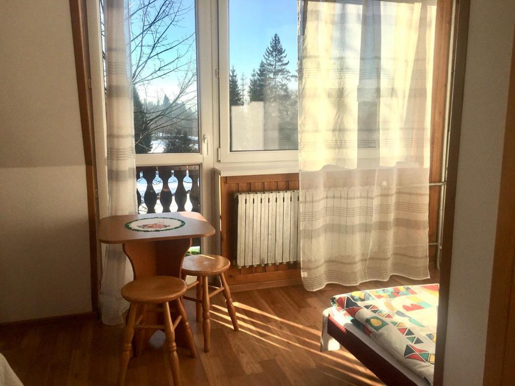 a room with a window and a table and two stools at U Wiesi in Poronin