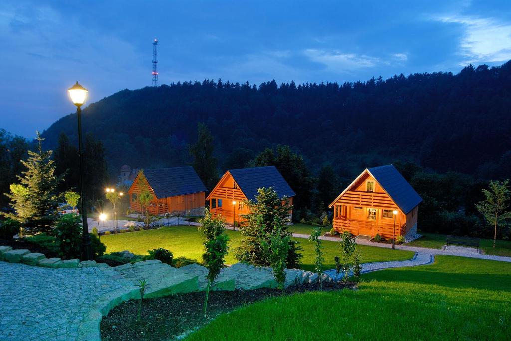 un grupo de cabañas de madera en un parque por la noche en Domki u Basi en Kudowa-Zdrój