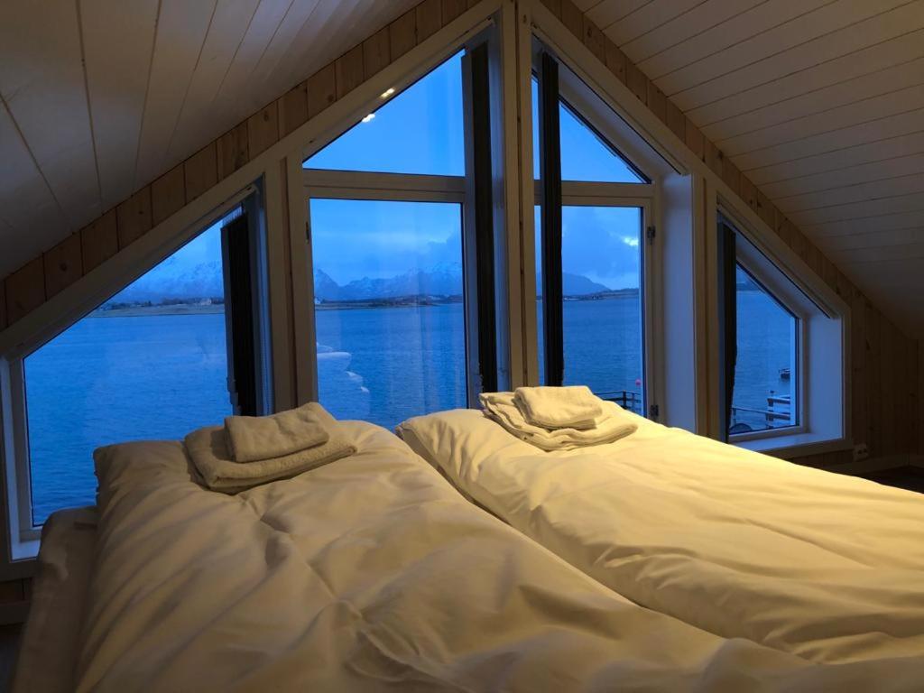 a bedroom with two beds in front of a large window at Rorbu Skreda in Leknes