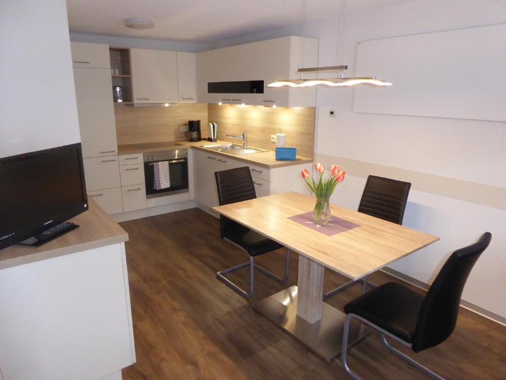 cocina con mesa de madera con sillas y TV en Ferienwohnung MOEWE, en Herdwangen-Schönach