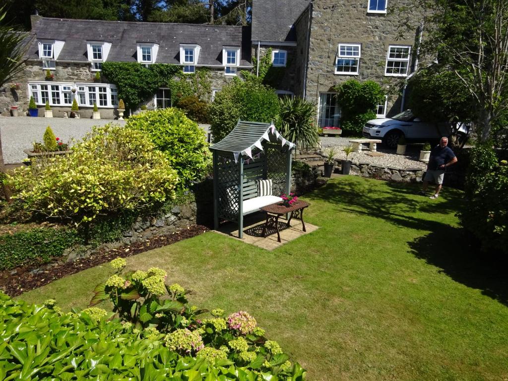 a man standing in a garden with a gazebo at Yr Hen Felin - The Old Mill B&B in Morfa Nefyn