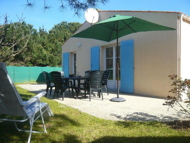 - une table et des chaises avec un parasol vert dans la cour dans l'établissement mamaisonaoleron 3ch-6pers calme terrain clos OLERON, à Grand-Village-Plage