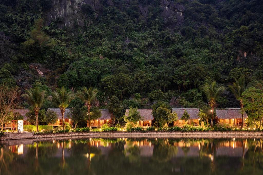 a house on the shore of a lake at night at An's Eco Garden Resort in Ninh Binh