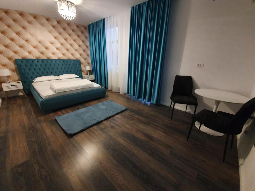 Schlafzimmer mit einem Bett, einem Tisch und Stühlen in der Unterkunft GARSONIERRE CENTRAL LUXURY in Târgu Jiu