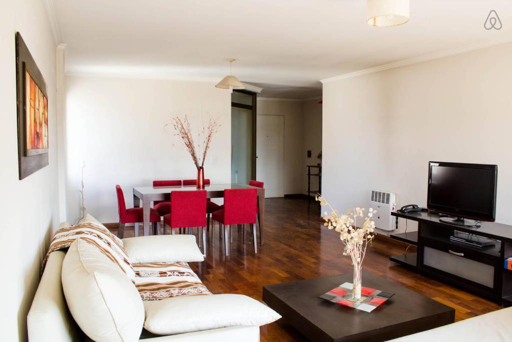 sala de estar con sofá y mesa con sillas rojas en Departamento enorme sobre Cañada Patio Olmos en Córdoba