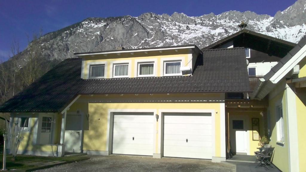 a house with two garage doors in front of a mountain at Ferienwohnung Stockenhuber in Sankt Martin am Grimming