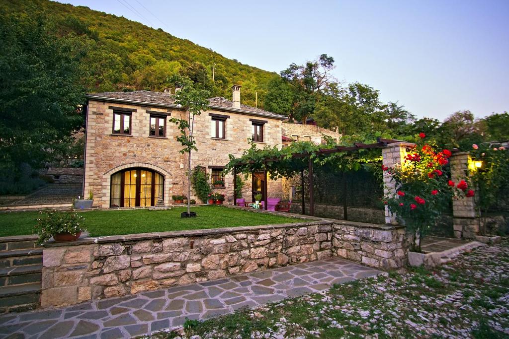 a stone house with a stone wall and a yard at Guesthouse Lucas in Zagori