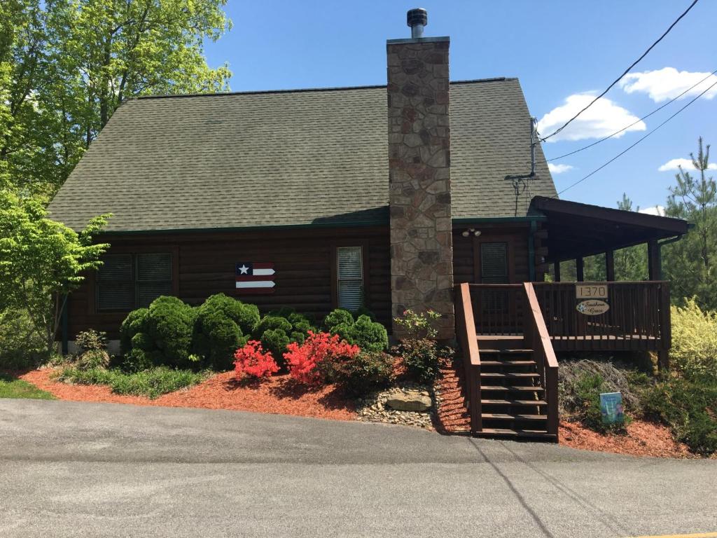 una casa de madera con porche y flores en la parte delantera en Southern Grace en Sevierville