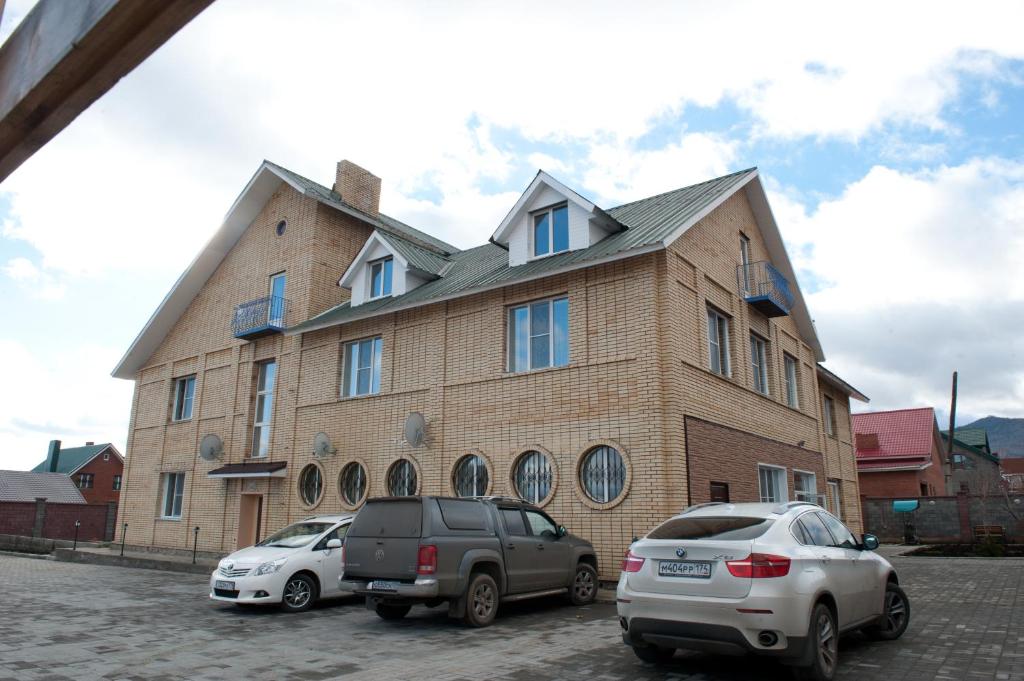 two cars parked in front of a large brick building at ApartHotel na Berezovoy in Zelenaya Polyana