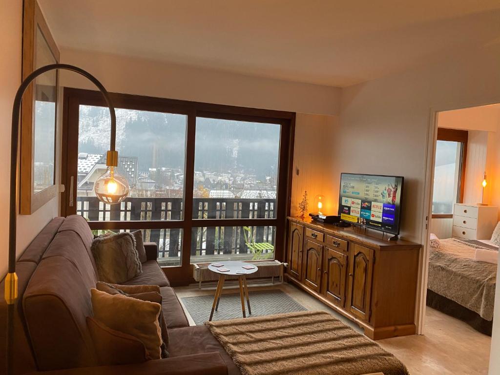 un salon avec un canapé et une grande fenêtre dans l'établissement Residence Du Brevent, à Chamonix-Mont-Blanc