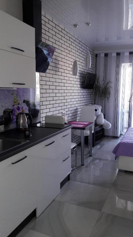 a kitchen with white cabinets and a table in it at Апартаменты. Холодная гора, ул. Дудинской 1а. in Kharkiv