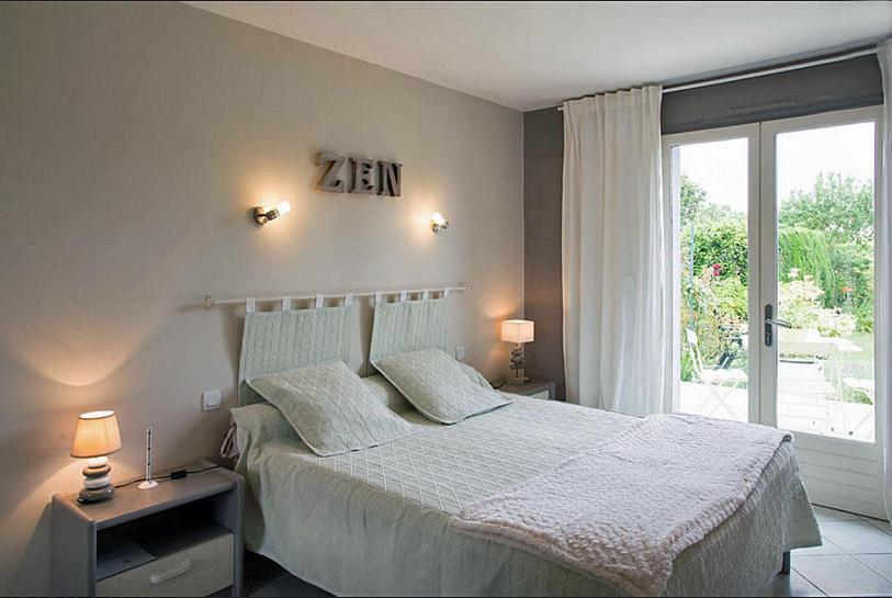 a bedroom with a bed with a zan clock on the wall at Chambre d'Hôtes aux Sables d'Olonne in Les Sables-dʼOlonne