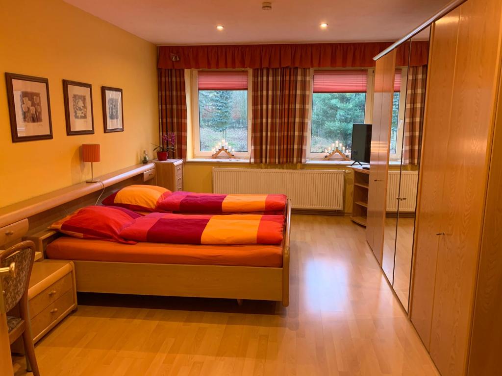 a bedroom with a bed with colorful sheets on it at Pension Pöhlbergblick Annaberg in Annaberg-Buchholz