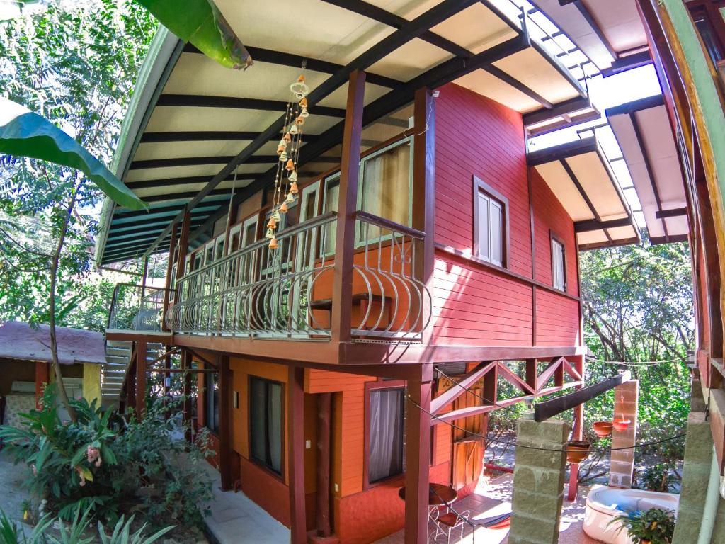 een huis met een veranda rondom en een balkon bij Coyote Rooms in Cabuya