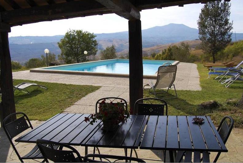 a blue picnic table with chairs and a swimming pool at Villa Il Cerro in Radicofani