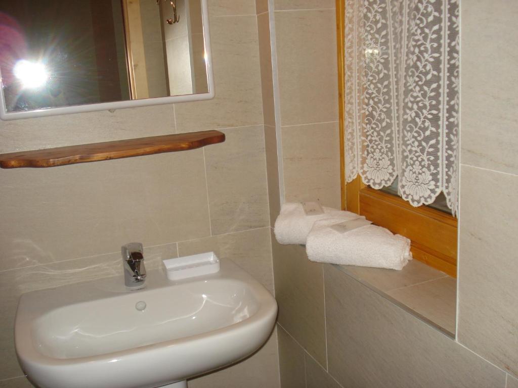 bagno bianco con lavandino e specchio di Rifugio Alpe Ponte a Chiesa in Valmalenco