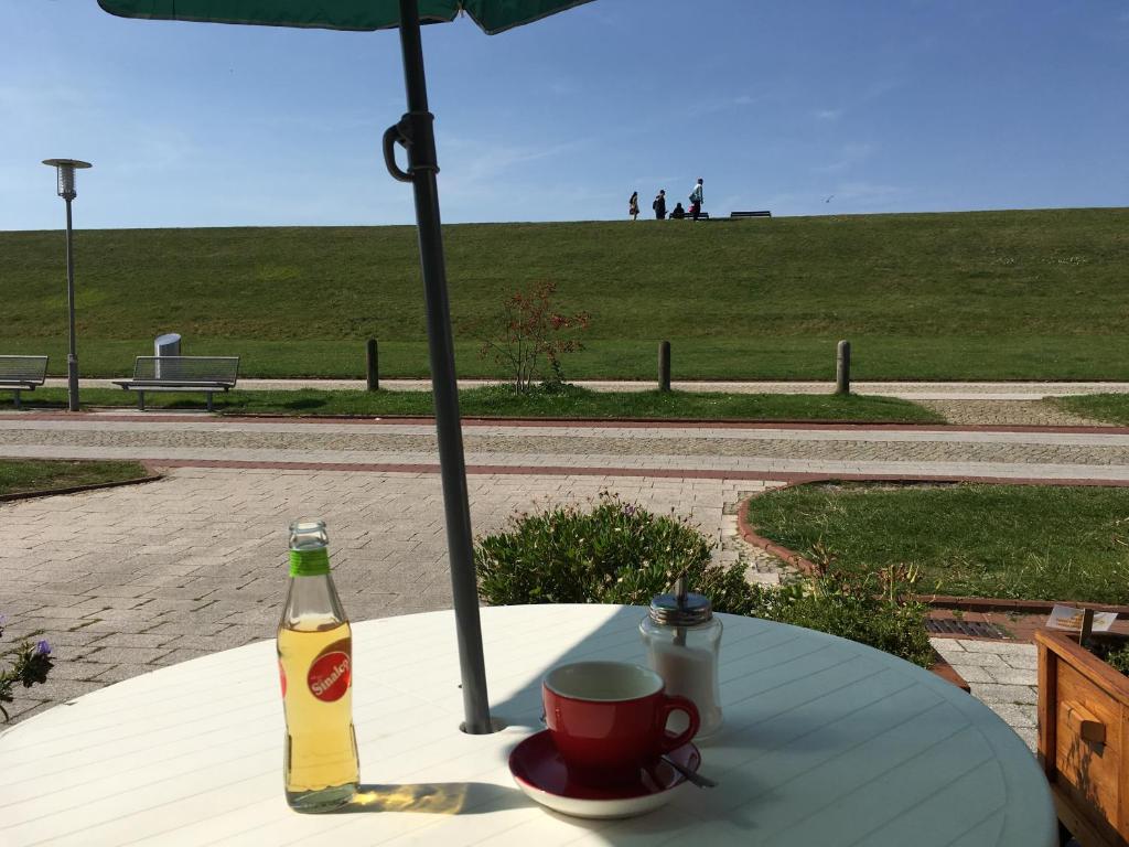 uma mesa com um guarda-chuva e uma bebida sobre ele em Kiekkast em Norddeich