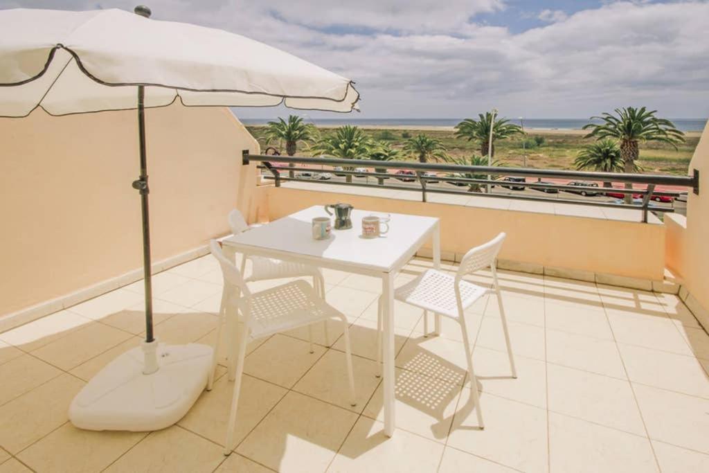 a white table with chairs and an umbrella on a balcony at terrazza e vista sull'oceano, Wi-Fi, piano 3, piscina sullo stesso piano in Morro del Jable