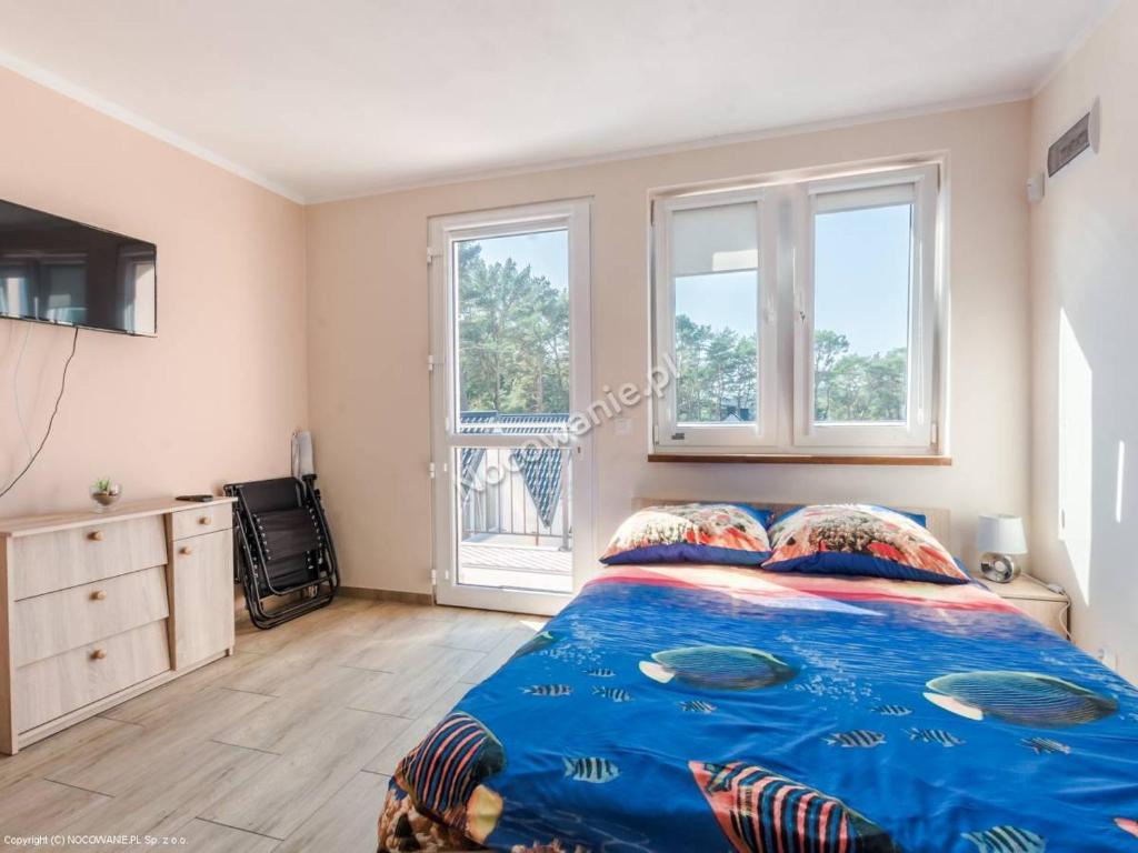 1 Schlafzimmer mit einem Bett mit blauer Decke und 2 Fenstern in der Unterkunft Liwia 2 in Niechorze