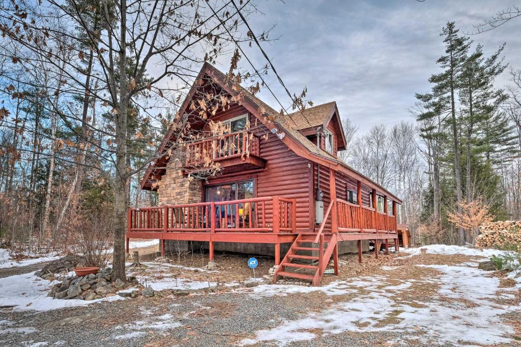 uma cabana de madeira com um deque na floresta em Secluded Johnsburg Outdoor Oasis - Private Hot Tub em Johnsburg