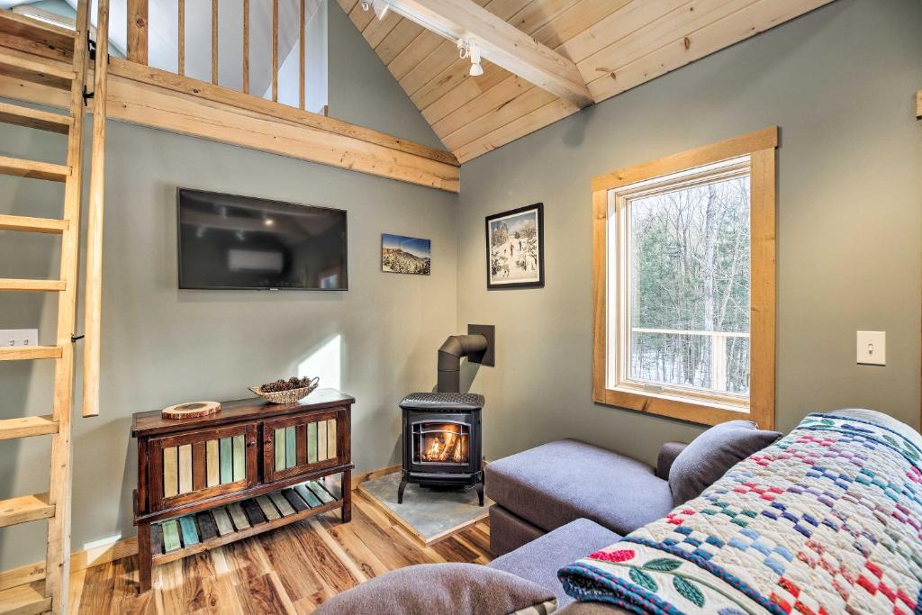 a living room with a couch and a wood stove at Newly Built Cabin with Hot Tub - 16 Mi to Stowe Mtn! in Morristown