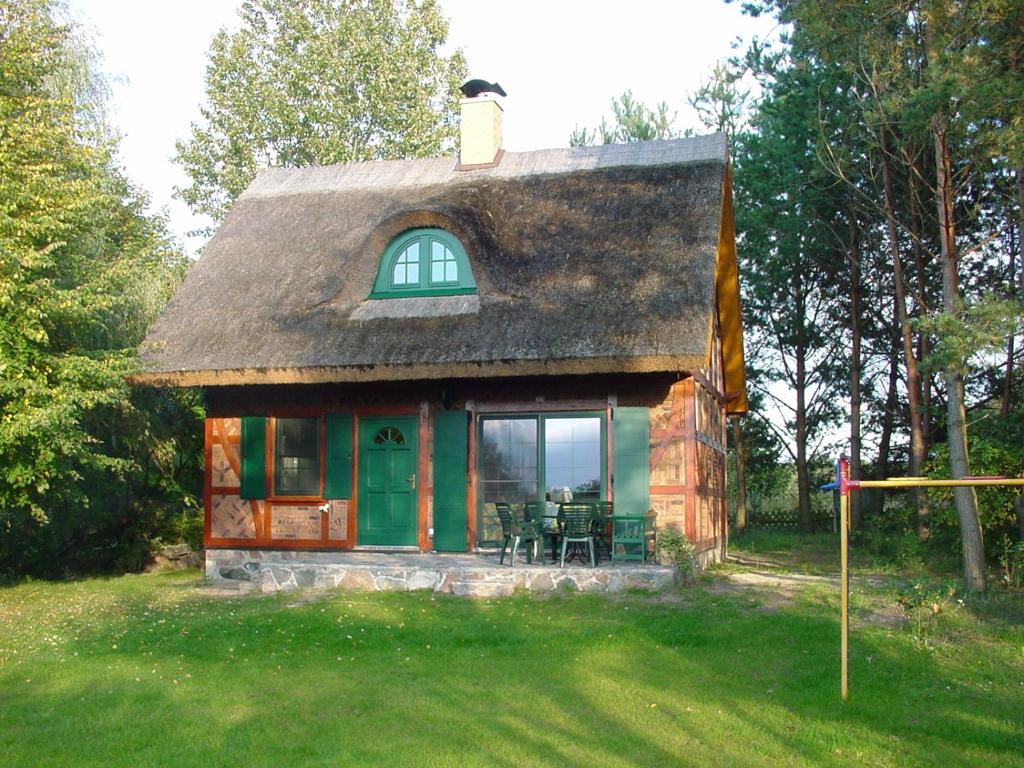 a small house with a thatched roof in the grass at Ferienhaus Am Eichler Stich in Zehdenick