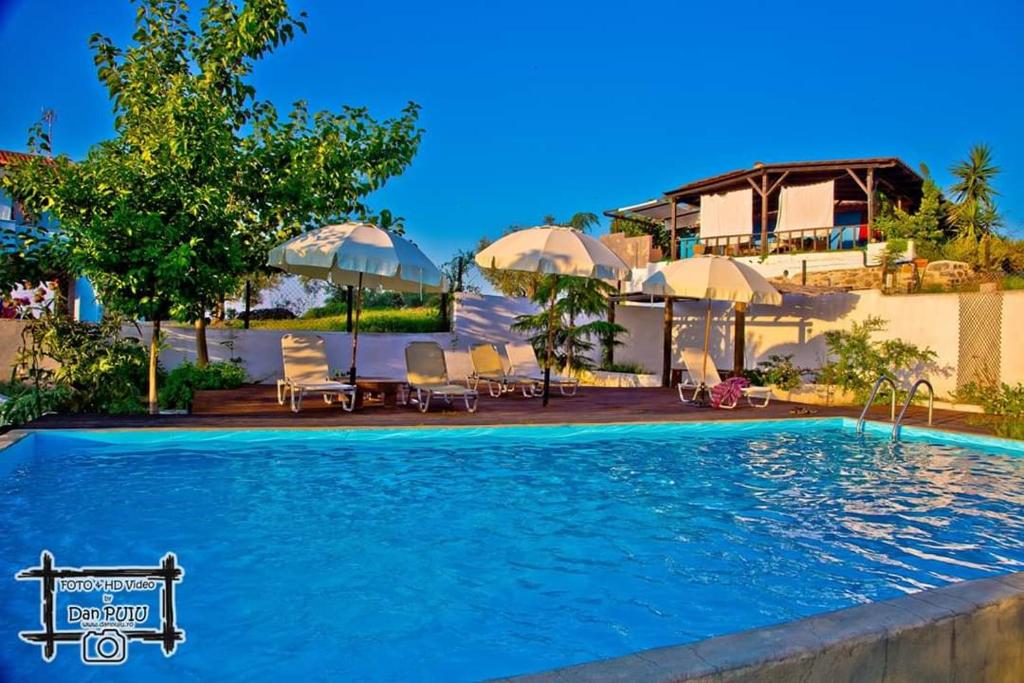 - une piscine avec des chaises et des parasols en face d'une maison dans l'établissement Lofos Vourvourou, à Vourvourou