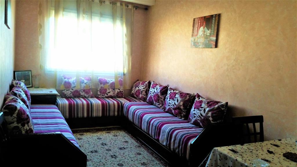 een woonkamer met een lange bank en kleurrijke kussens bij Appart au Centre de Rabat مرحبا in Rabat