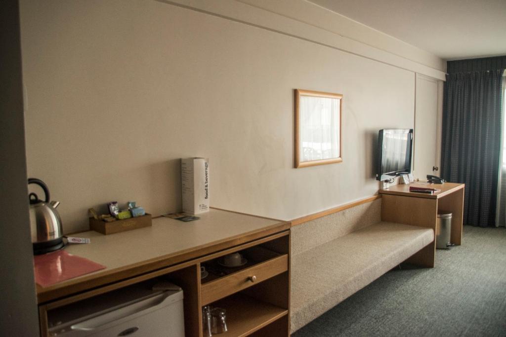 a hotel room with a desk and a couch in a room at Heartland Hotel Queenstown in Queenstown