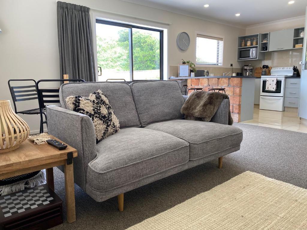 a living room with a gray couch and a kitchen at The Klein House in Whanganui