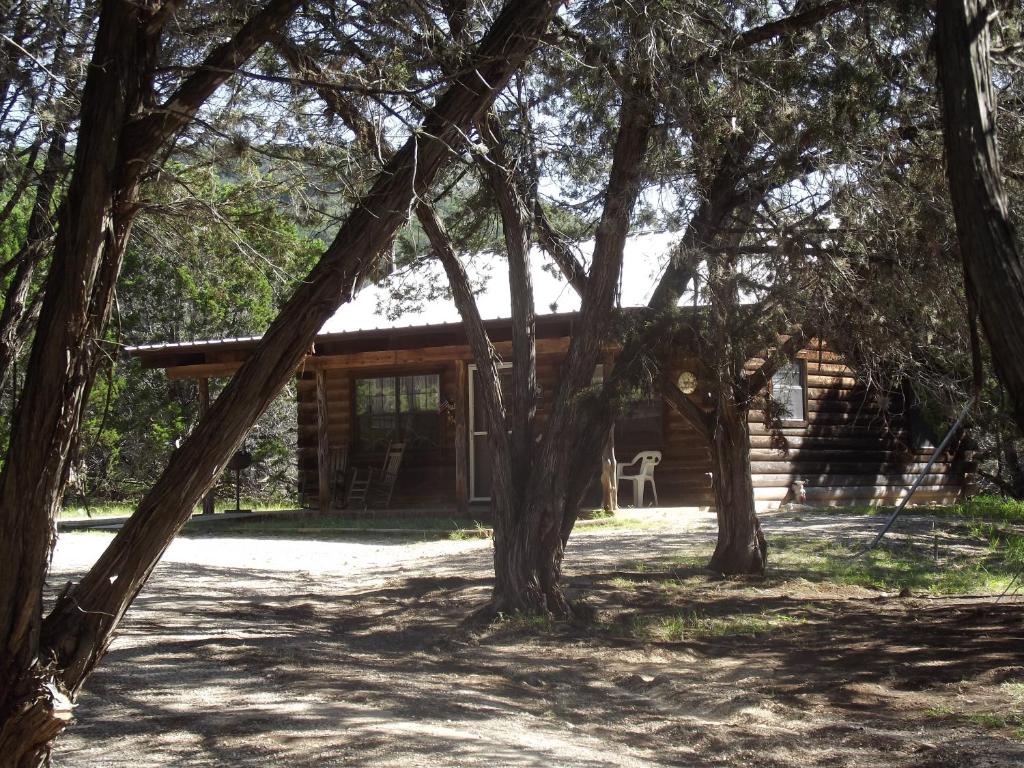 a log cabin with trees in front of it at A Peace of Heaven Cabins and RV in Vanderpool