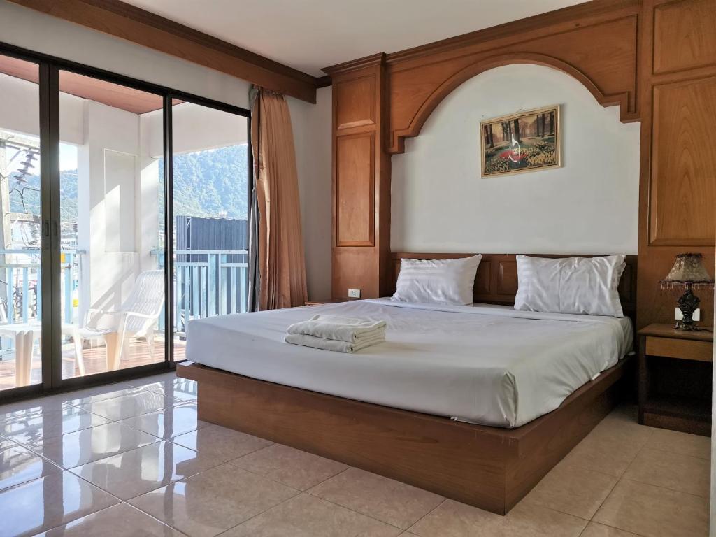a bedroom with a large bed and a balcony at Praew Mansion in Kamala Beach