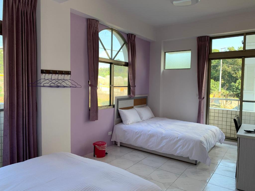 two beds in a bedroom with purple walls and windows at Jin Ji Homestay in Minxiong