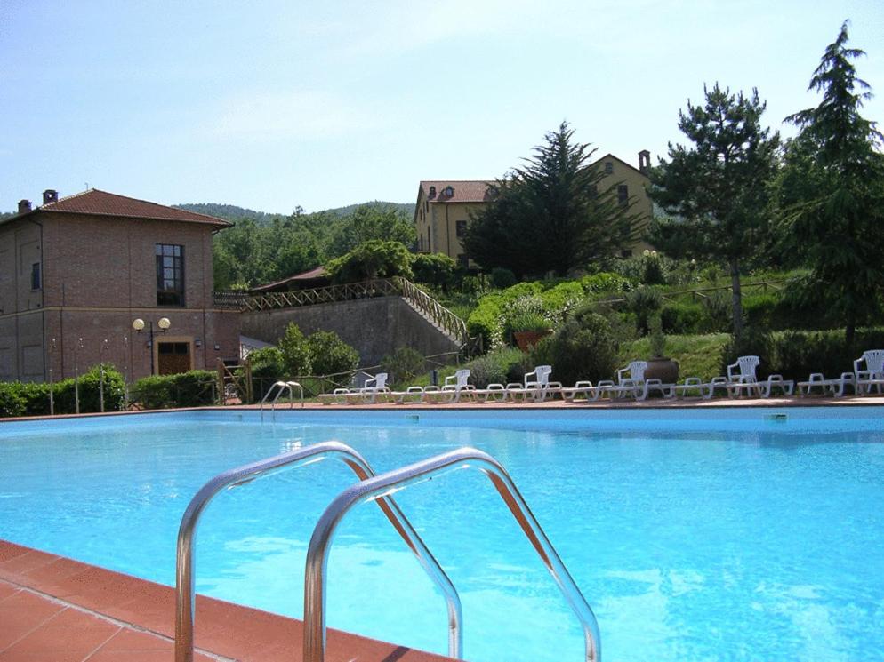 una gran piscina con sillas y un edificio en Hotel Residence Sant'Uberto, en Roccastrada