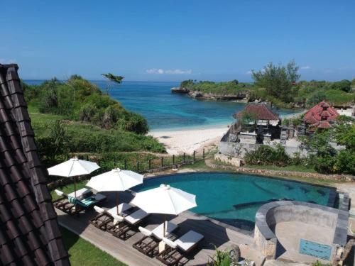 uitzicht op een zwembad met parasols en een strand bij D'byas Dream Beach Club and Villa in Nusa Lembongan